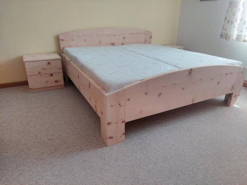 Zirbenbett mit geschwungenen Kopfteil und Nachtkästchen